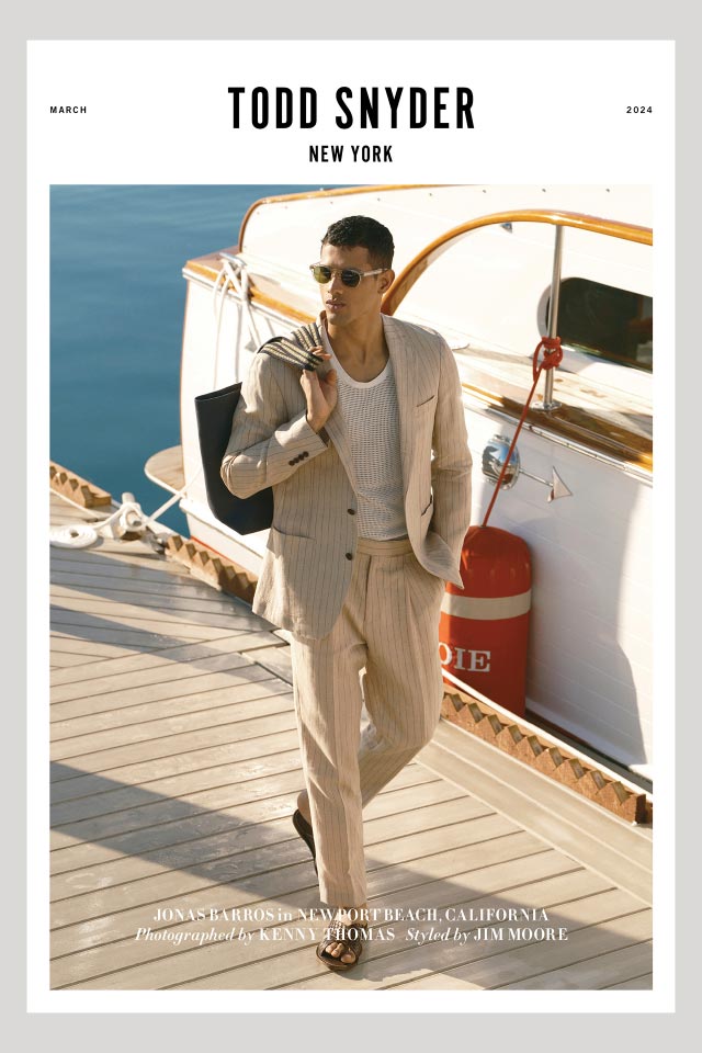 The cover of the Todd Snyder March catalog, featuring a man in a striped linen suit and sunglasses walking down a dock near a boat.