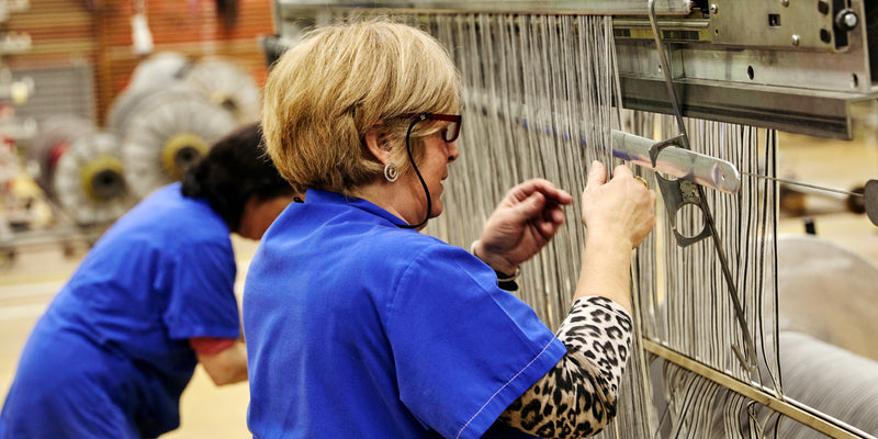 A craftsman is shown working on a fabric loom.