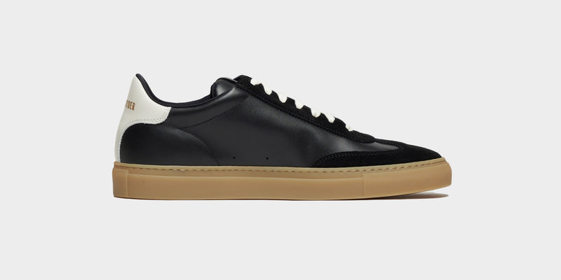 A black sneaker is shown with both leather and suede craftmanship.