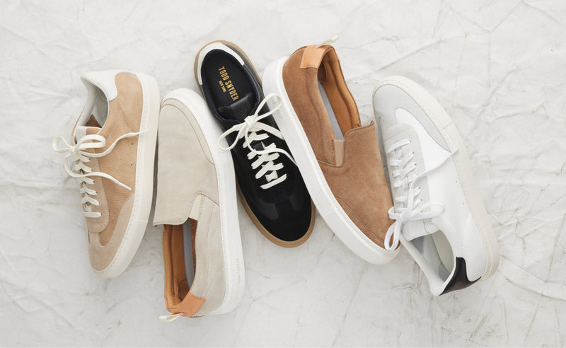 Different styles and colors of leather and suede sneakers are shown.